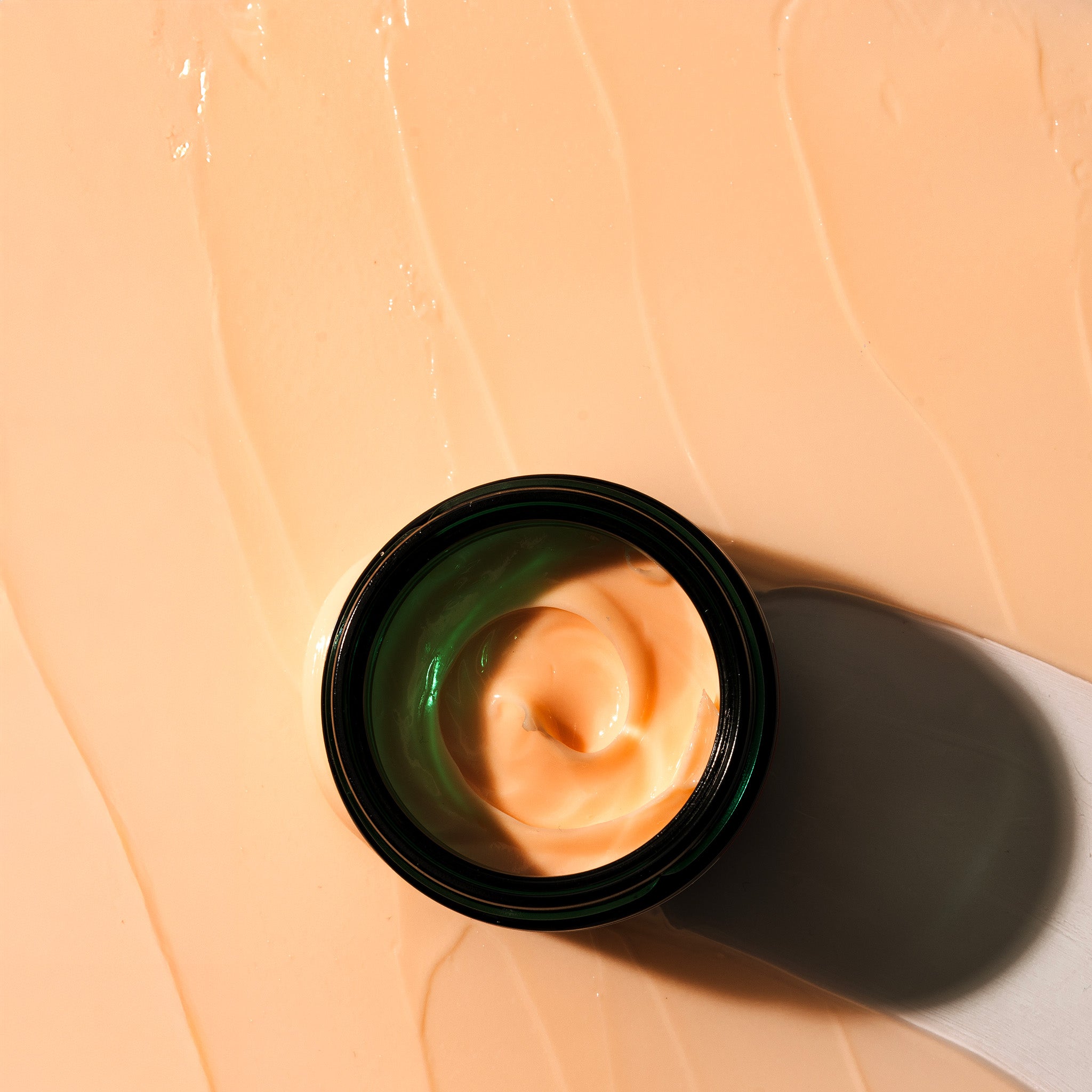 Birds eye view showing the texture of The Body Shop Glow Boosting Moisturiser, with an open jar in the centre of the picture