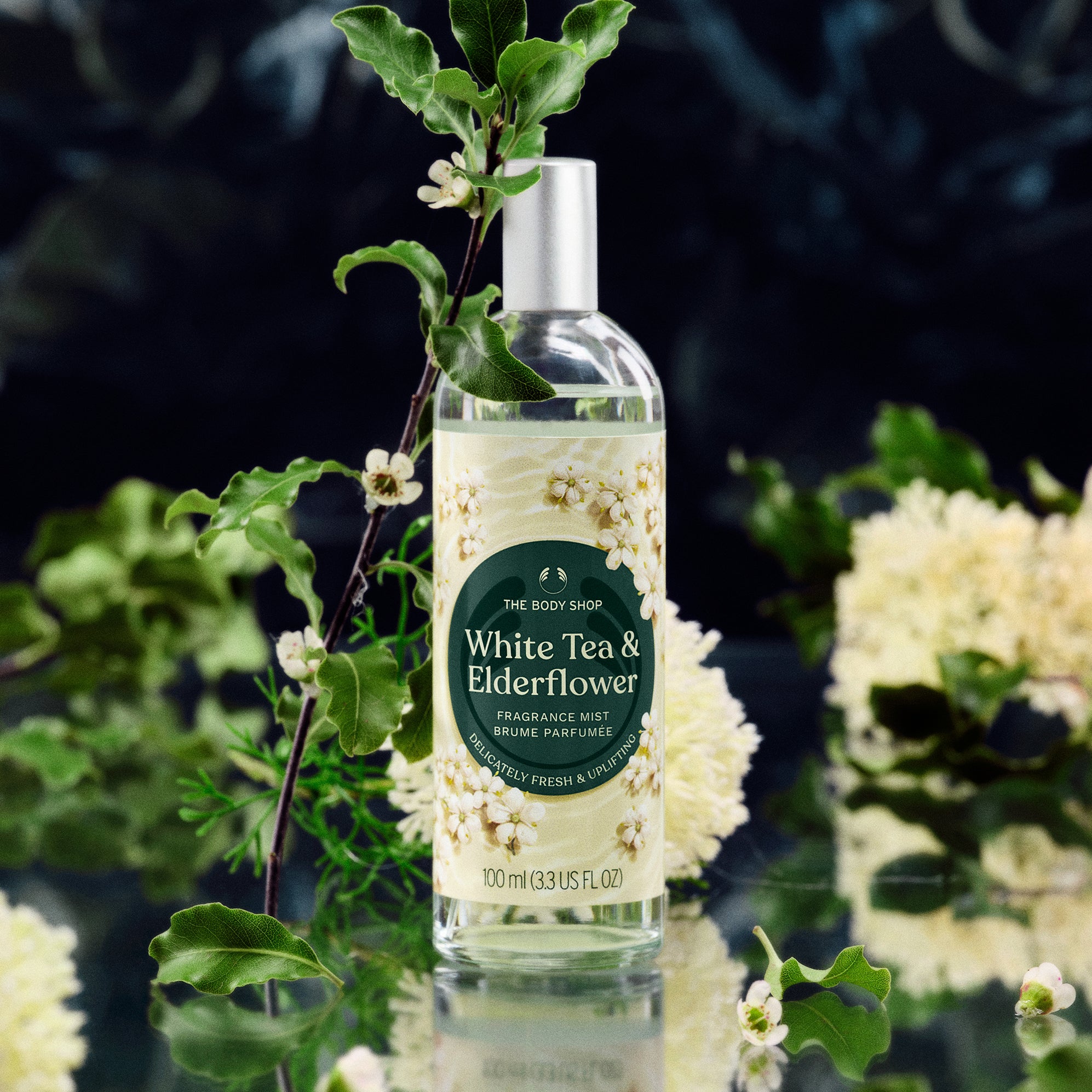 Fragrance mist bottle labeled 'White Tea & Elderflower' with green leaves and flowers in the background